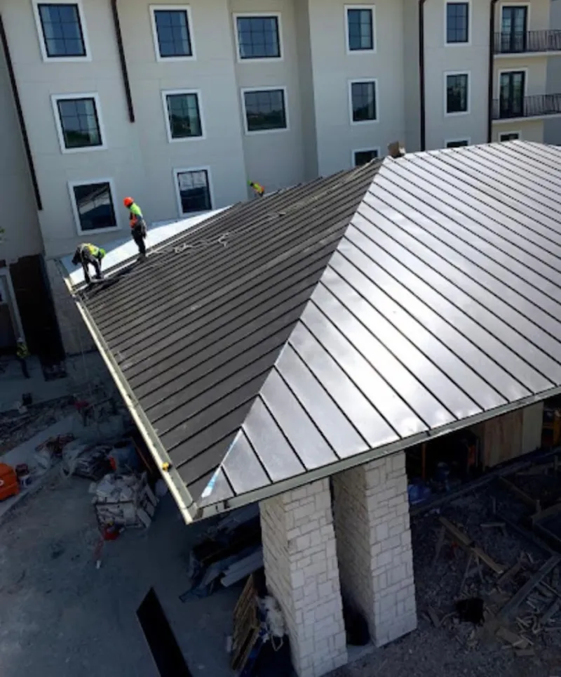 Crew installing standing seam metal roof panels on a commercial project in Tucson Mountains